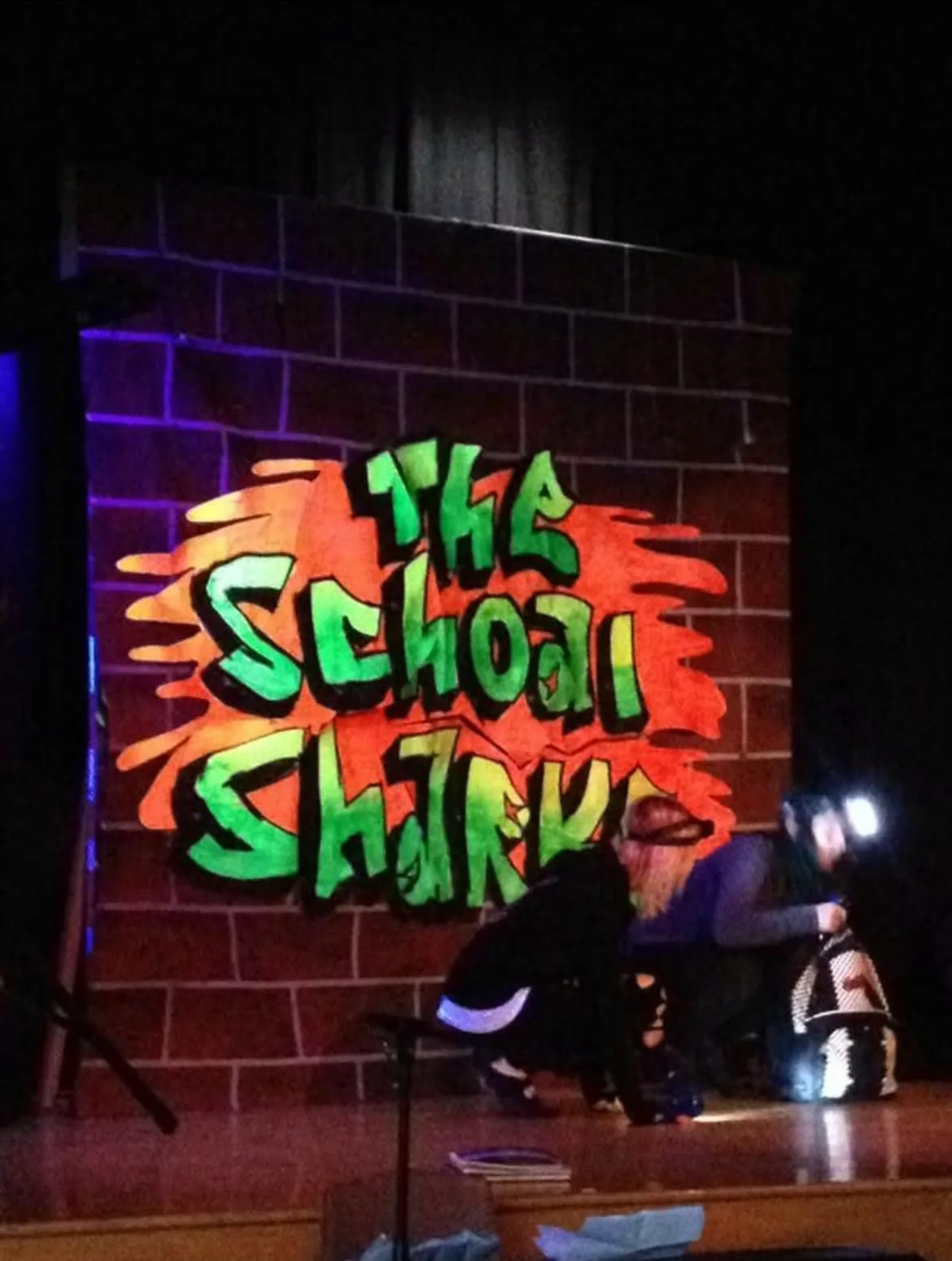 The School Sharks graffiti-style scenic backdrop in use onstage at Keswick High School in 2015